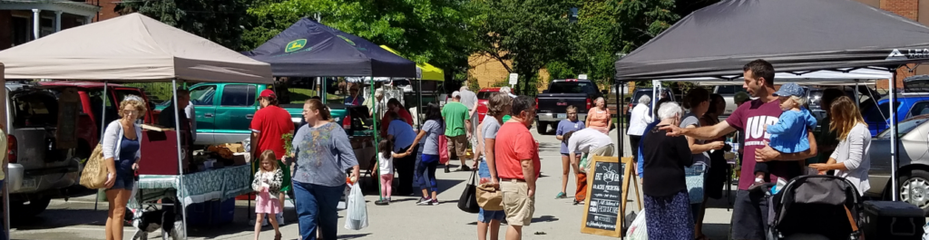visitors browsing goods at the farmers market tents